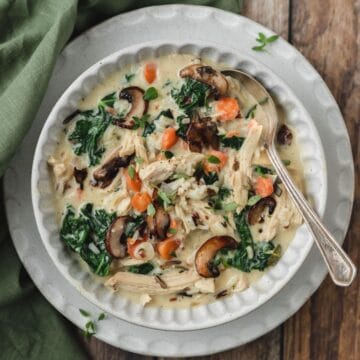 close up of bowl chicken wild rice soup with kale and mushrooms