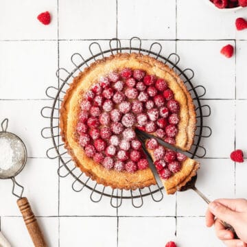 close up shot of raspberry almond frangipane tart with fresh raspberries on top