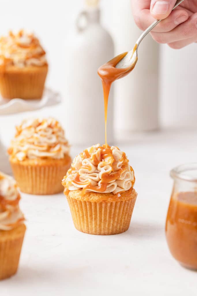salted caramel being drizzled on brown butter cupcake