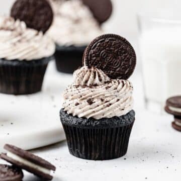close up of cookies and cream cupcakes with oreo on top.