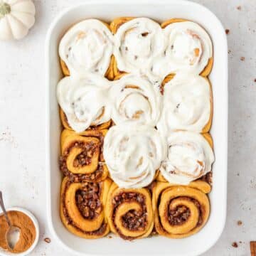 close up of pumpkin spice cinnamon rolls with maple and pecans.