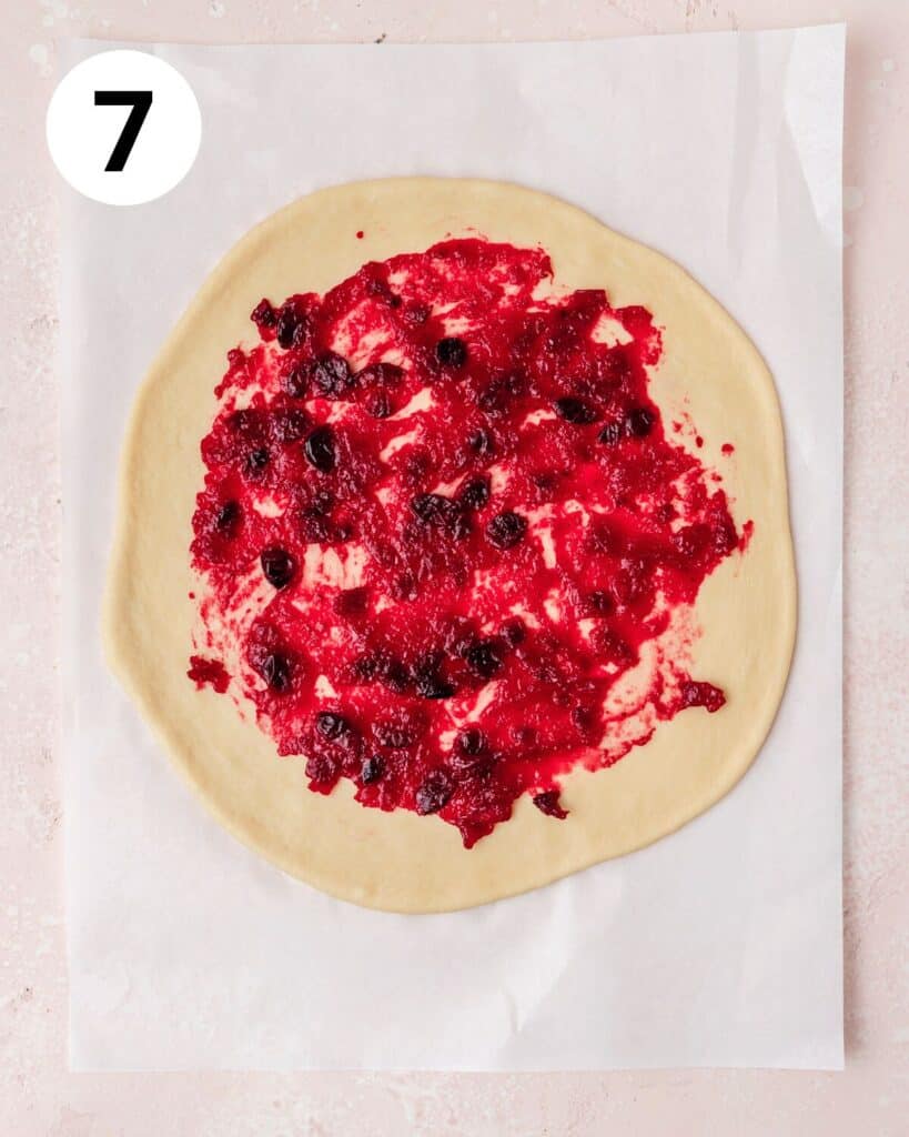 spreading cranberry sauce on dough.