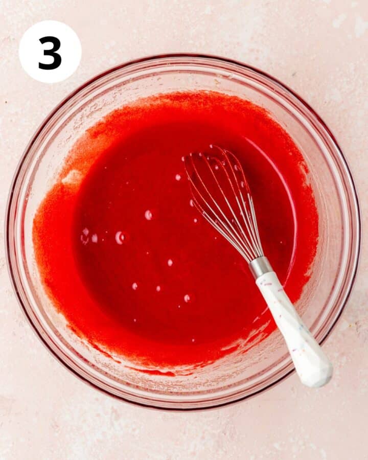 adding red food coloring to cake batter.
