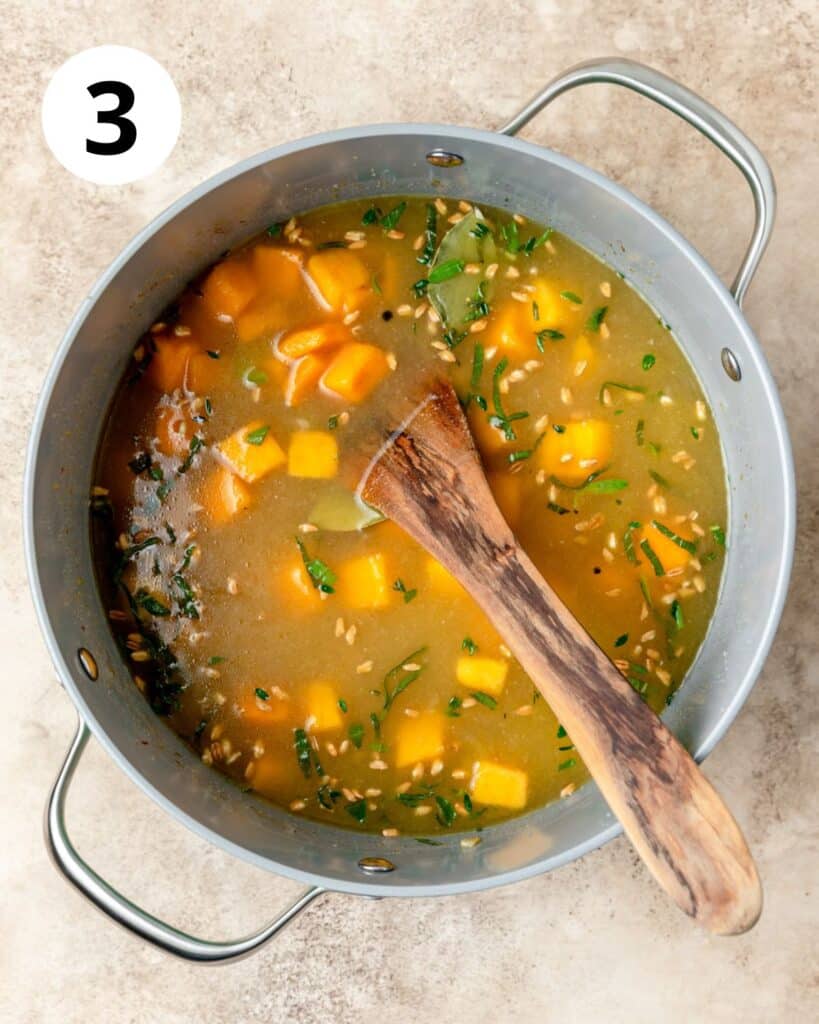 adding broth and barley to soup.