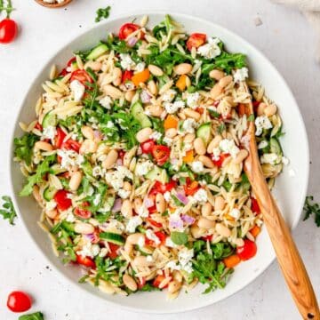 close up of bowl of orzo white bean salad with arugula.