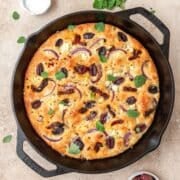 close up of cast iron focaccia with sundried tomatoes and Kalamata olives.