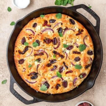 close up of cast iron focaccia with sundried tomatoes and Kalamata olives.