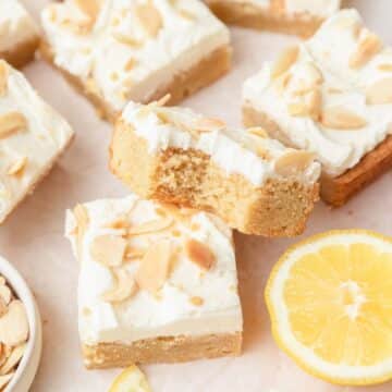 close up of frosted lemon sugar cookie bars with almonds.