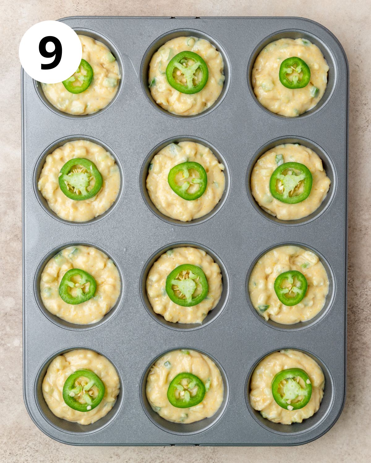 jalapeno cheddar cornbread muffins topped with jalapeno slices before baking.