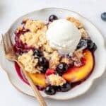 close up of peach blueberry cobbler with vanilla ice cream.