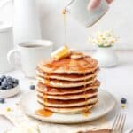 close up of stack of sourdough discard pancakes being drizzled with syrup.