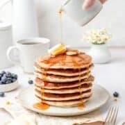 close up of stack of sourdough discard pancakes being drizzled with syrup.