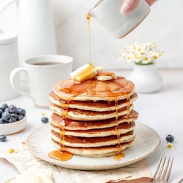 close up of stack of sourdough discard pancakes being drizzled with syrup.