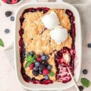close up of mixed berry cobbler topped with vanilla ice cream.