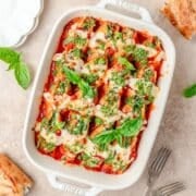 close up of spinach stuffed shells topped with fresh pesto.