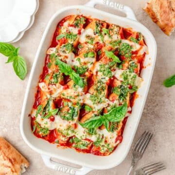 close up of spinach stuffed shells topped with fresh pesto.