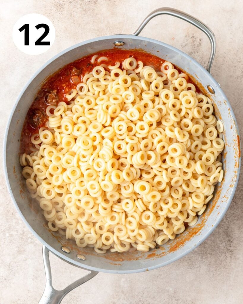 adding cooked anelli pasta to sauce.
