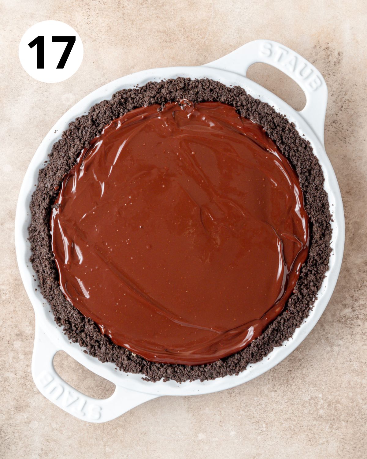 pouring chocolate ganache over peanut butter pie filling.