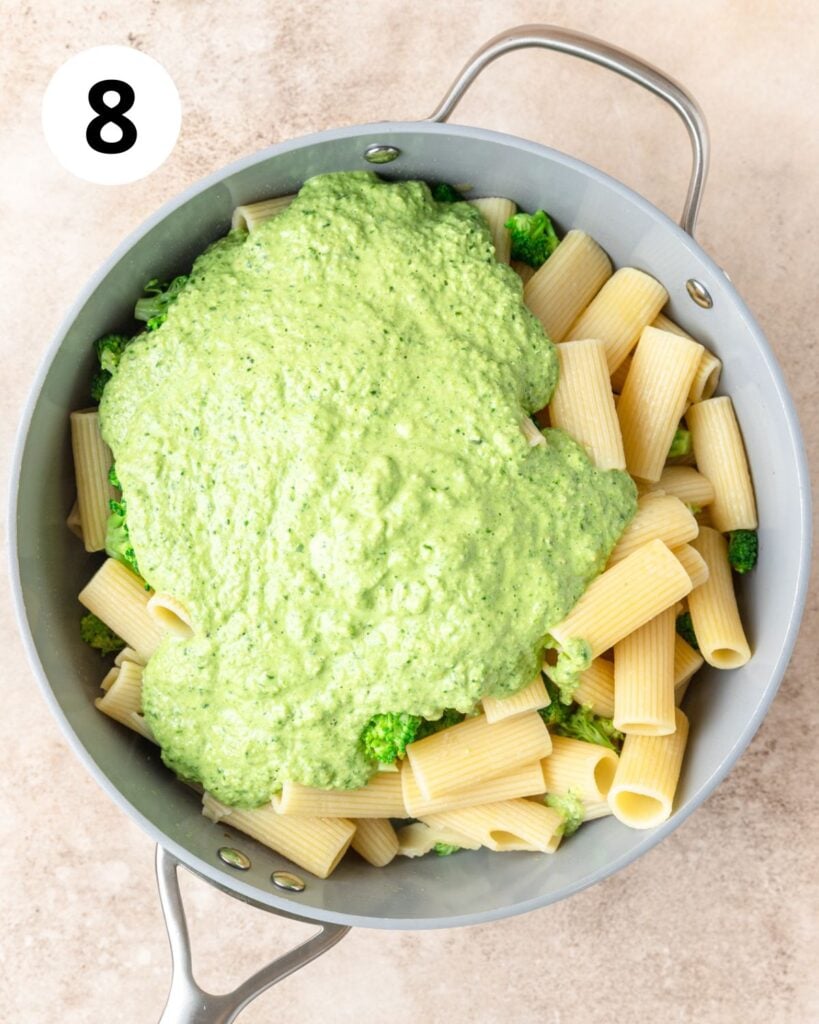 adding broccoli pesto sauce to pasta.