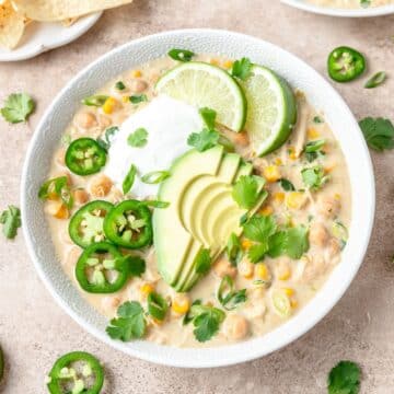 close up of creamy white chicken chili topped with sliced avocado.