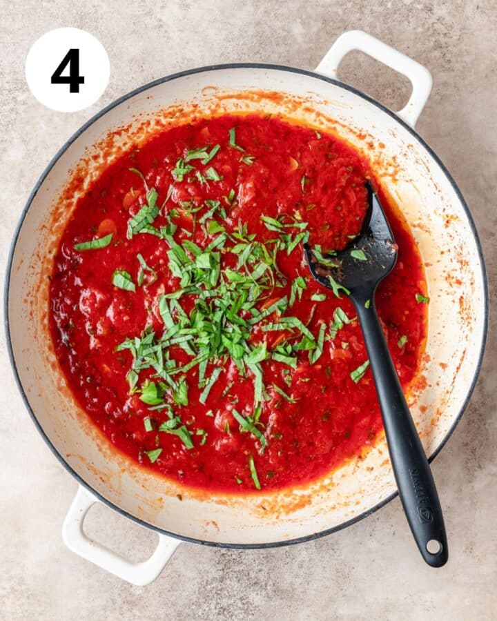 adding basil and oregano to pizza sauce.