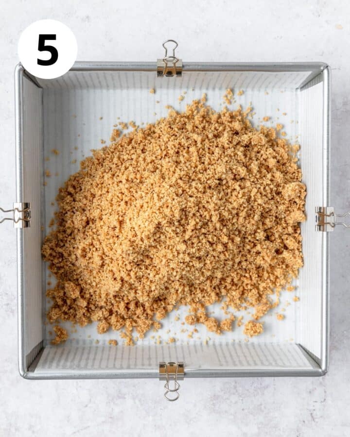 adding graham cracker crust to square pan.