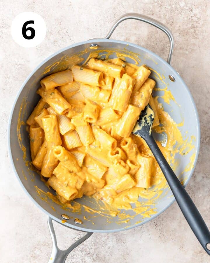 tossing pasta in pumpkin sauce.