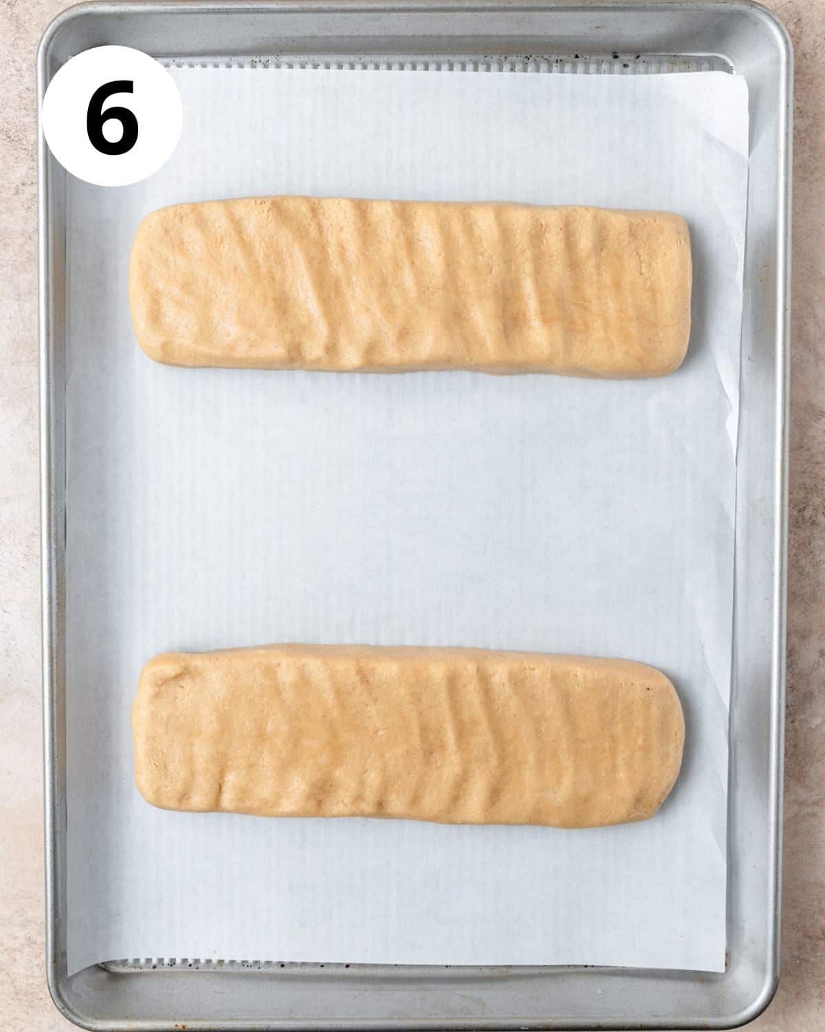 two logs of cookie butter biscotti dough formed on baking sheet.