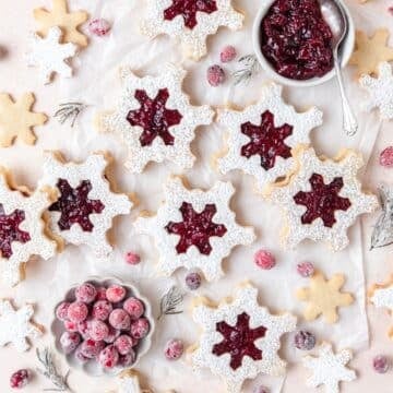 close up of snowflake shaped cranberry Linzer cookies.
