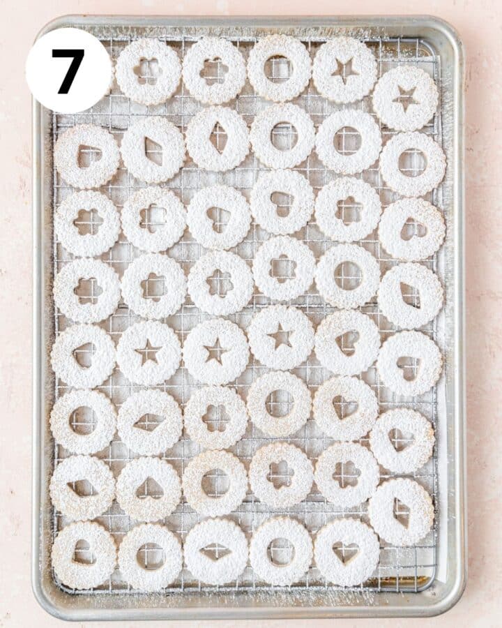 dusting tops of linzer cookies with powdered sugar.