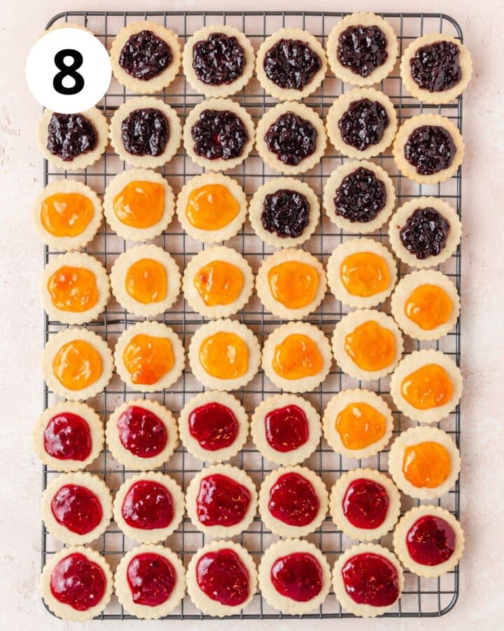 filling bottoms of linzer cookies with jam.