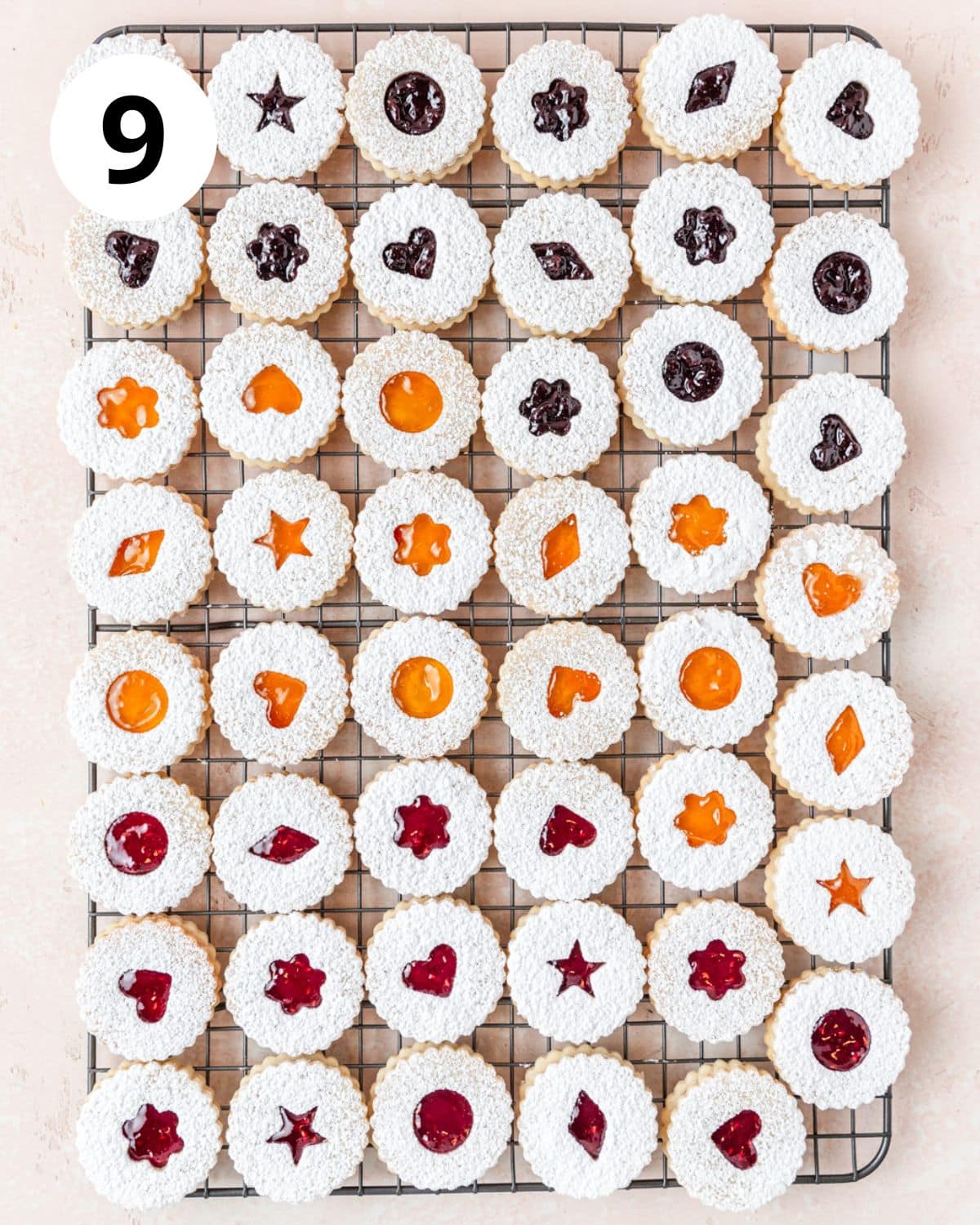 topping linzer cookies with powdered sugar half.