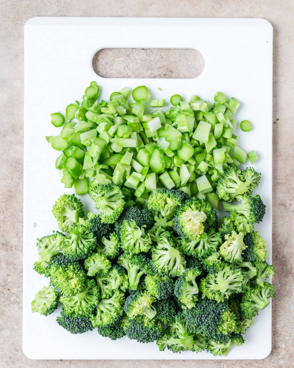 broccoli stems finely chopped and broccoli florets on cutting board.