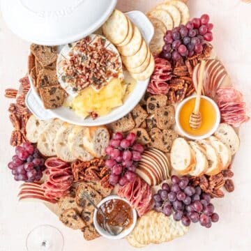 baked brie with honey and pecans on serving board.