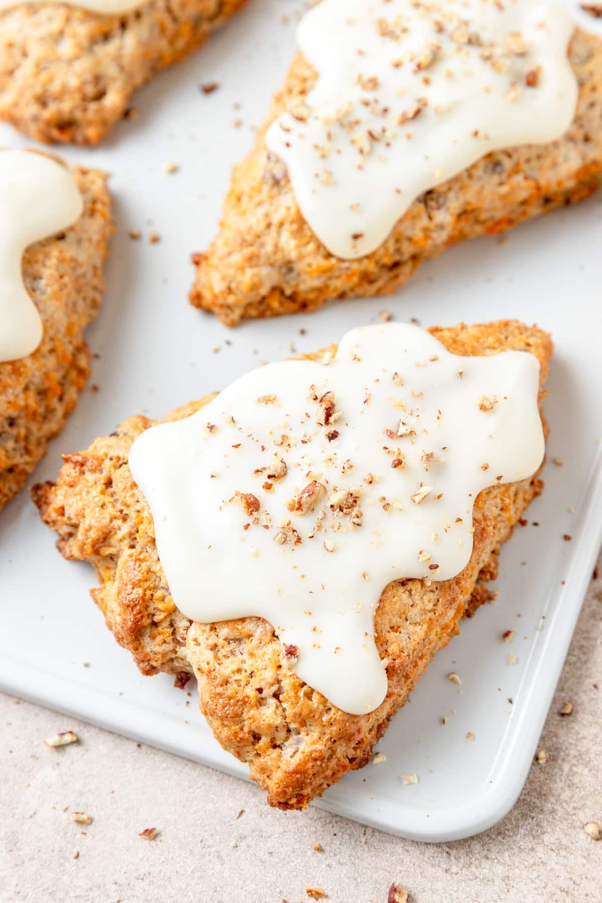 carrot cake scones with cream cheese frosting and pecans.