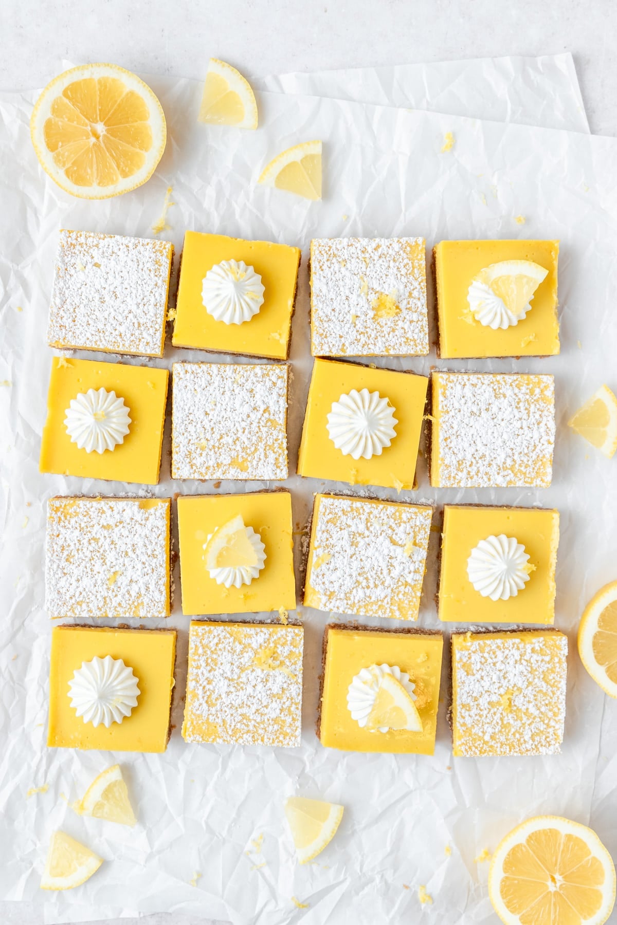 homemade lemon bars topped with powdered sugar and whipped cream.