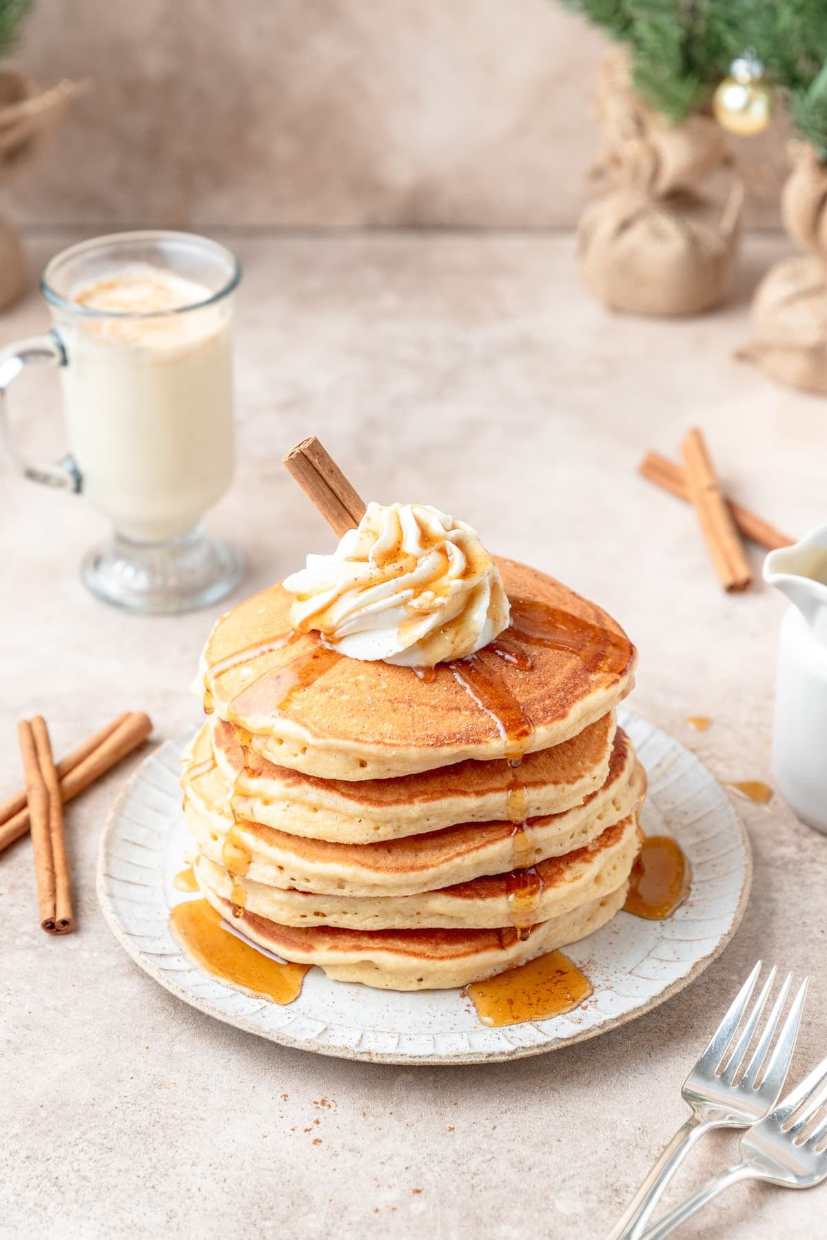 spiced eggnog pancakes topped with whipped cream and maple syrup.
