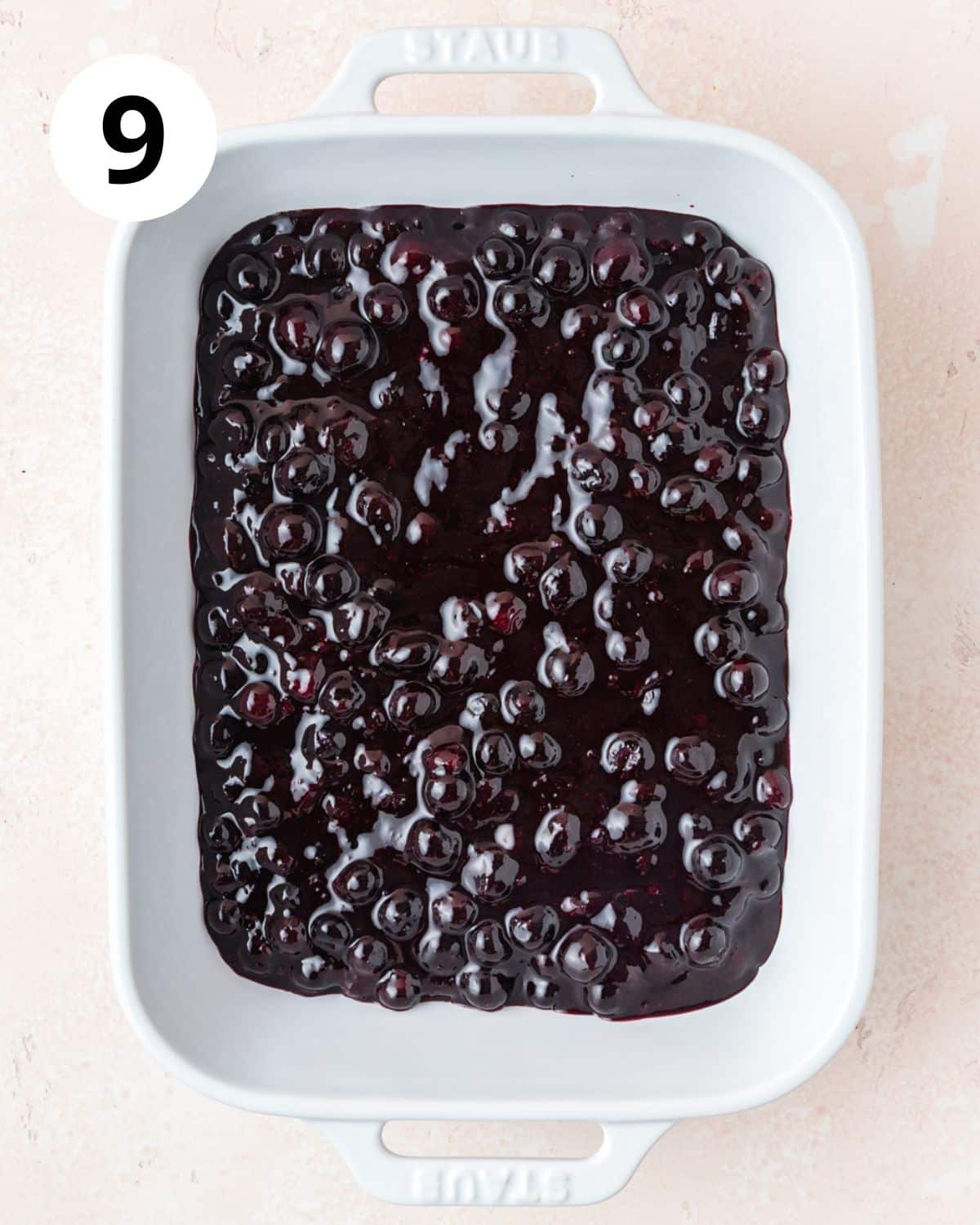 adding cooked blueberries to baking dish.